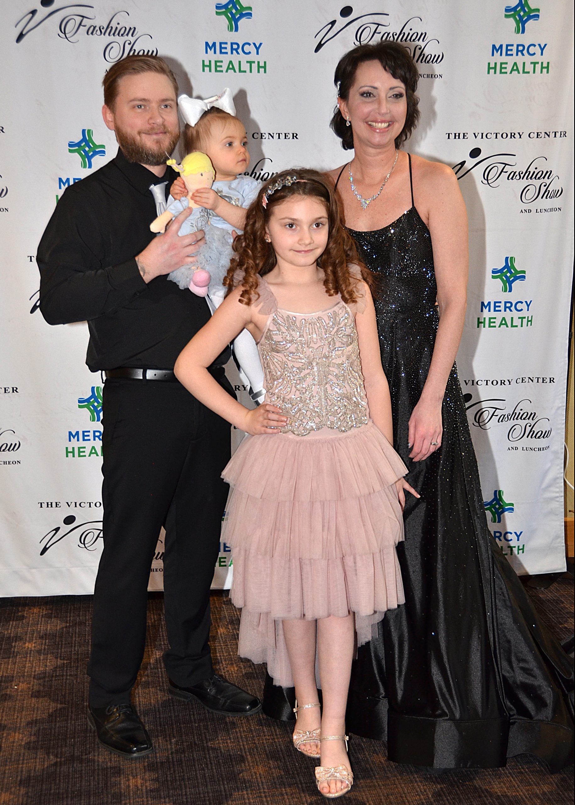 Family posing at an event; two adults and two children in formal attire.