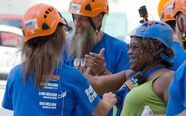 People in helmets and blue shirts, smiling and preparing for an activity.