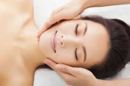 Relaxed woman receiving a facial massage with eyes closed.