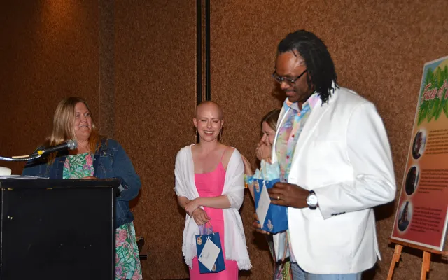 Four people stand together, one at a podium, smiling.