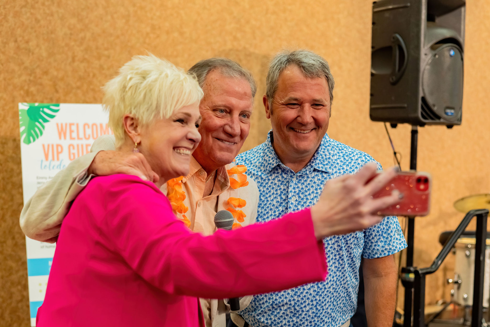Three people smiling and taking a selfie at an indoor event.