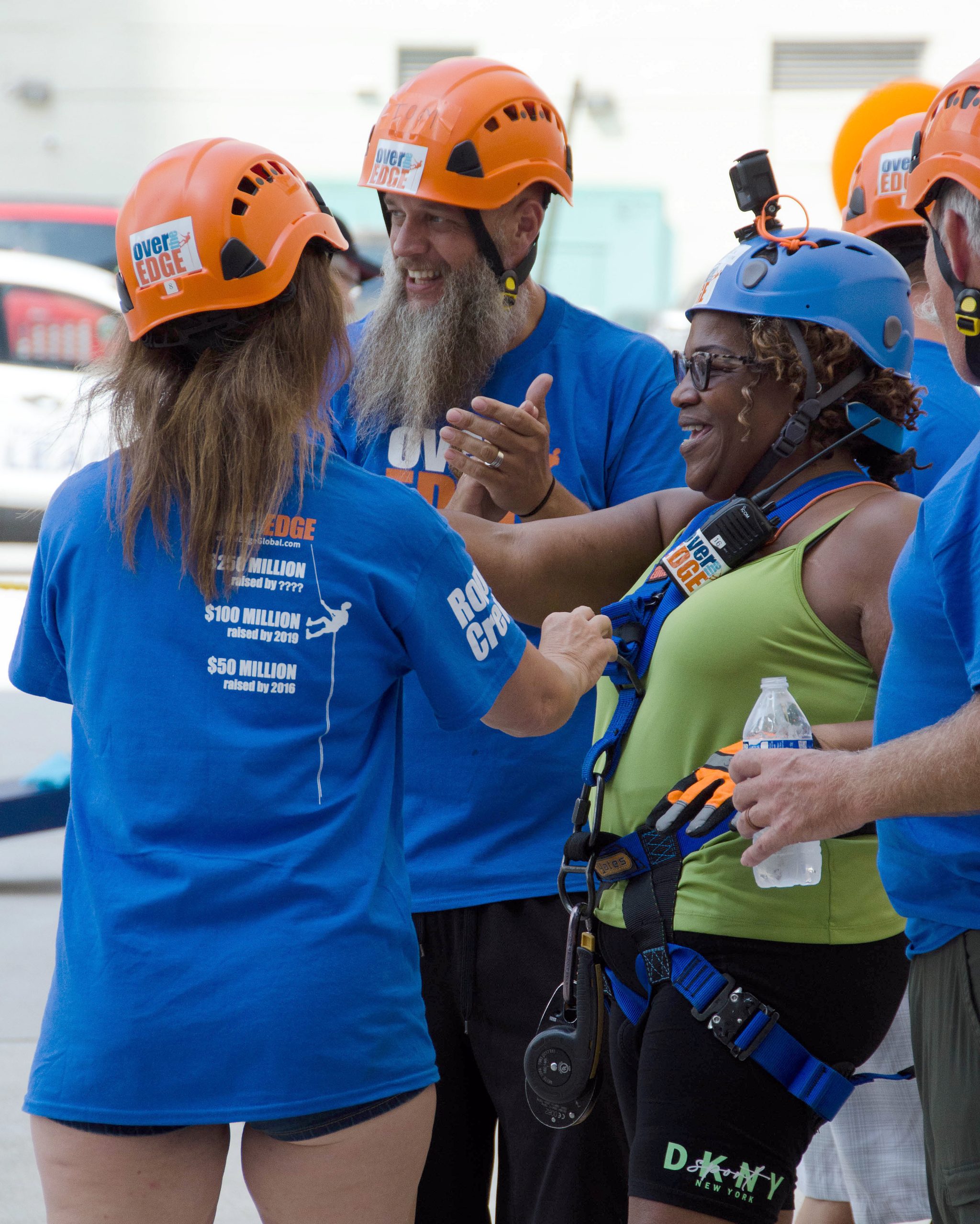 People in helmets and blue shirts, smiling and preparing for an activity.