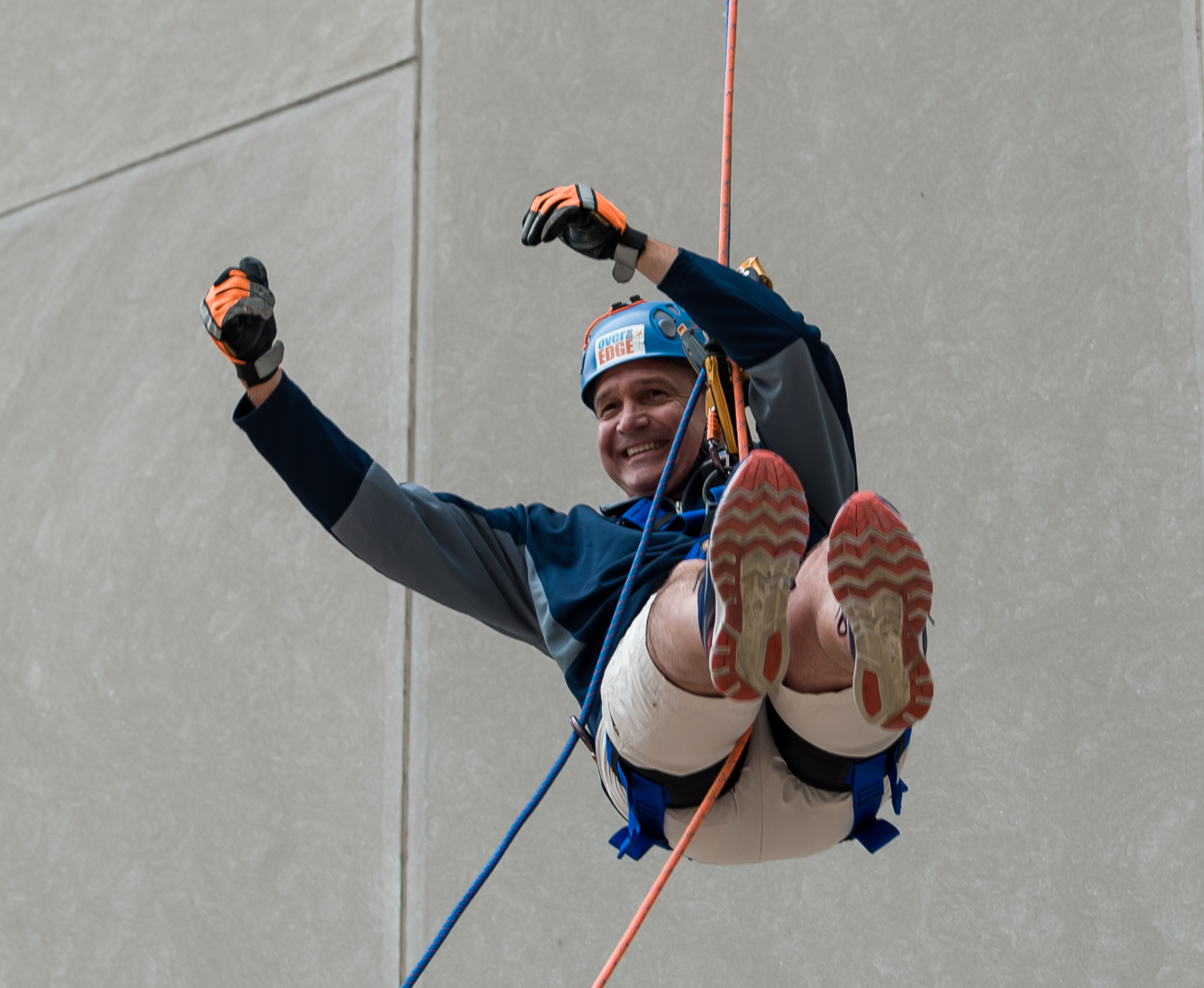 Person joyfully rappelling down a building wall.
