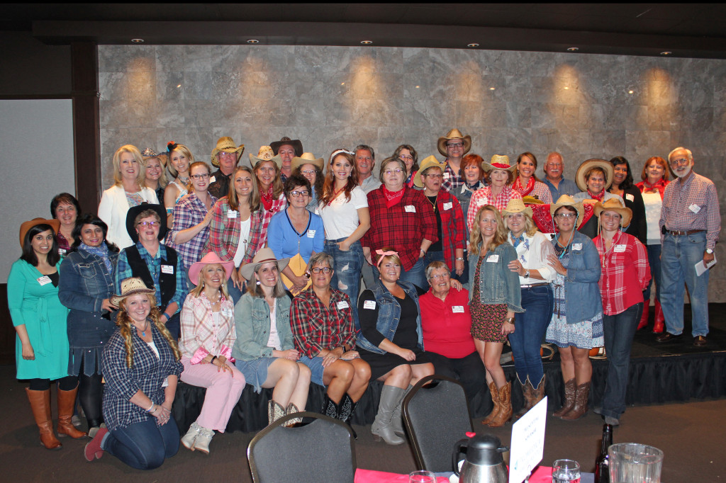 Group of people in casual and western attire smiling at a gathering.